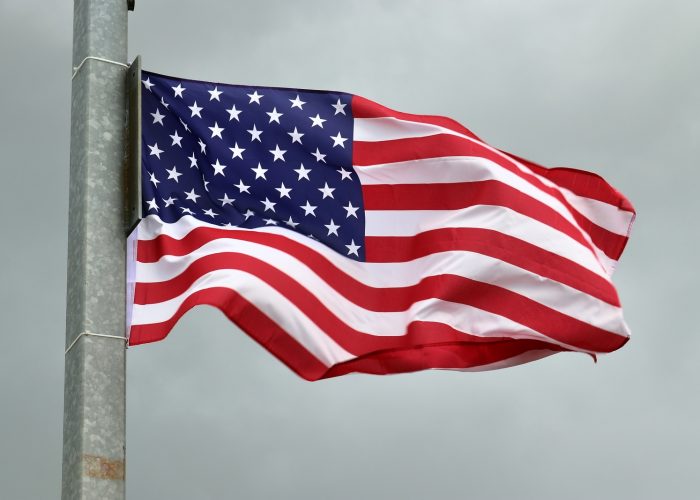 33145484_usa-flag-at-a-flagpole-moving-slowly-in-the-wind-against-the-sky